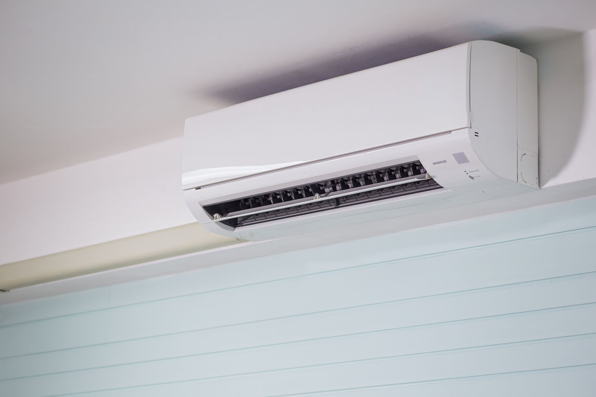The indoor unit of a split air conditioning system mounted high on a wall (illustrative stock photograph)