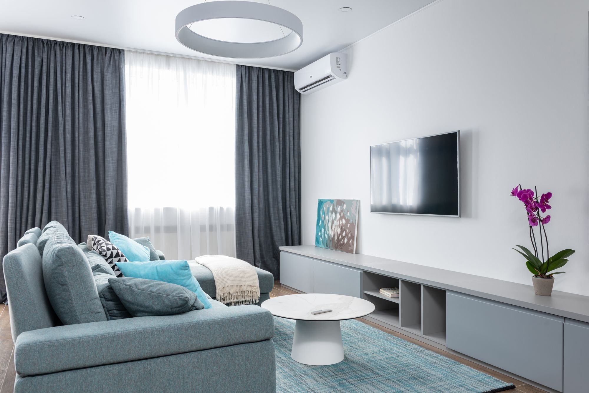 A wall-mounted air conditioning unit above the window of a living room (illustrative stock photograph)
