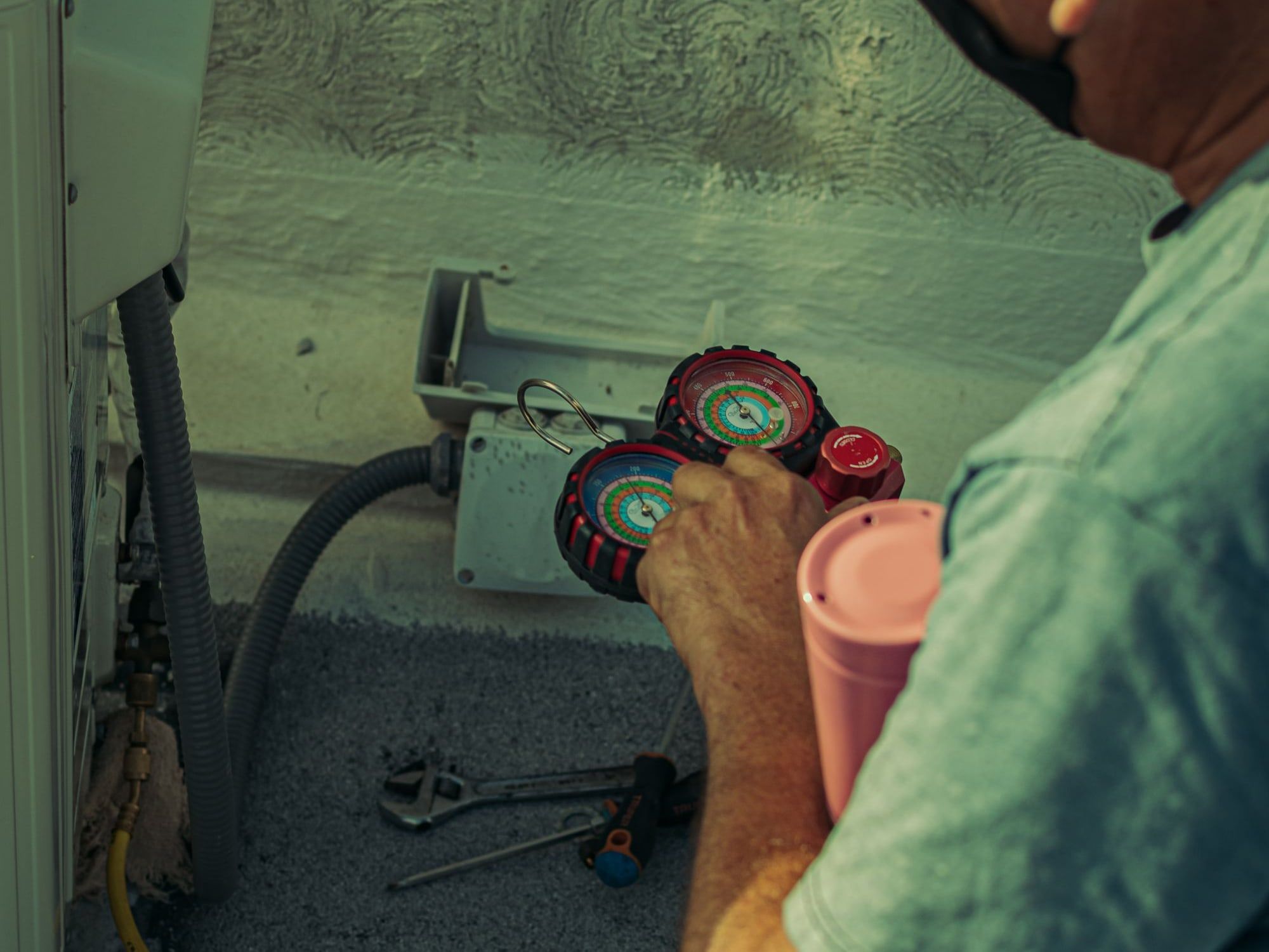 An engineer reading refrigerant gauges connected to an outdoor unit (illustrative stock photograph)
