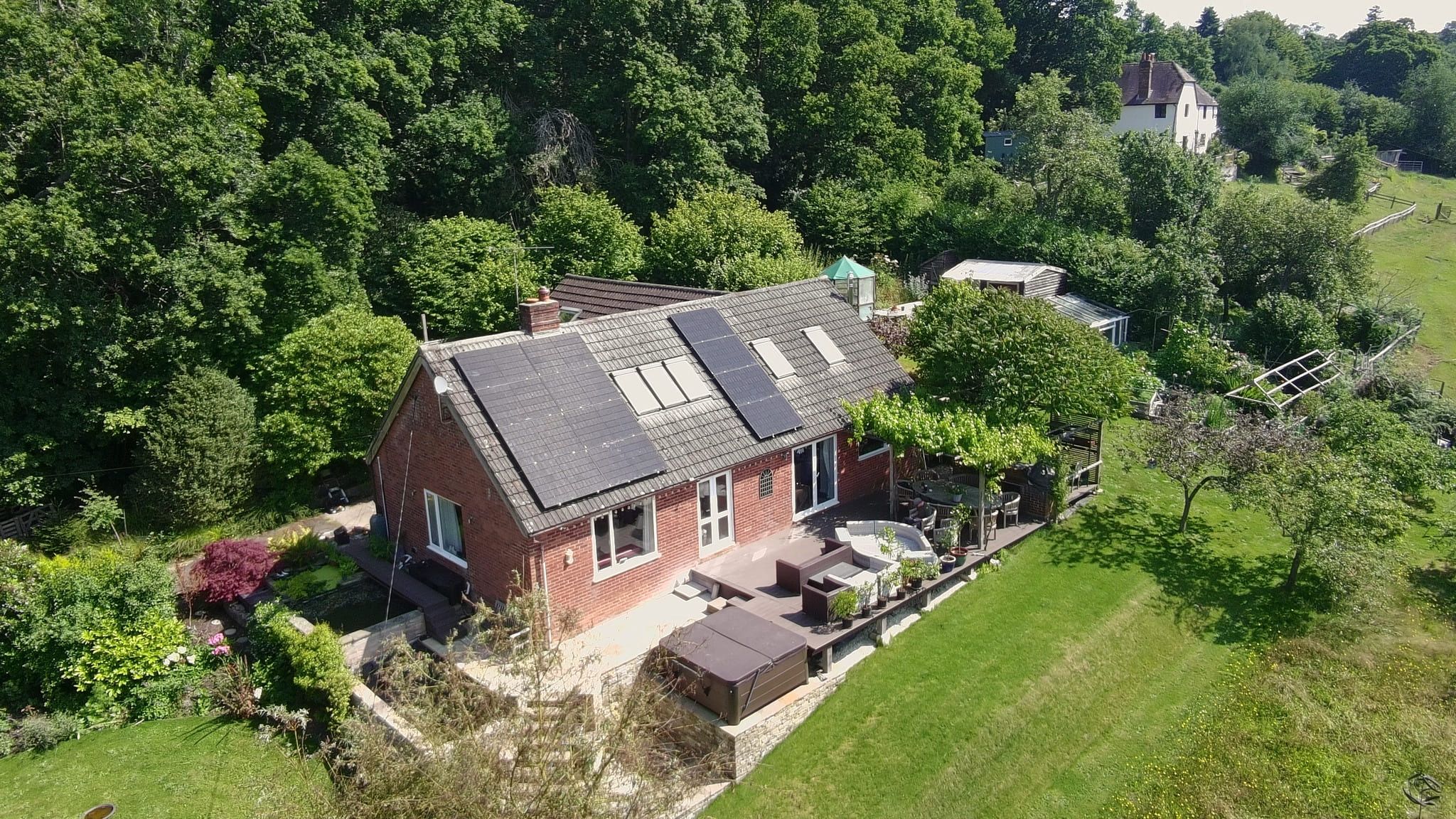 Aerial view of a Solar Squirrel install — a red-brick bungalow with solar panels in a green Sussex garden
