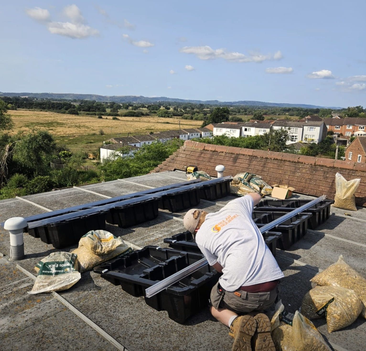 Mounting trays set out on a flat roof with fields beyond