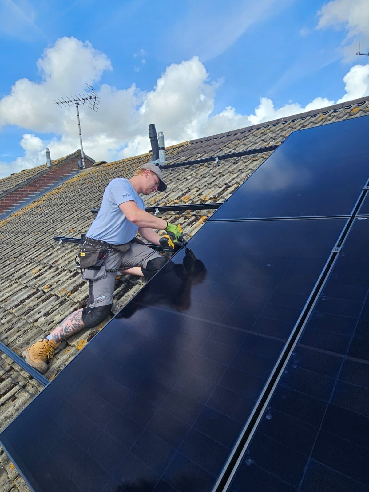A Solar Squirrel installer fixing all-black panels to a tiled roof