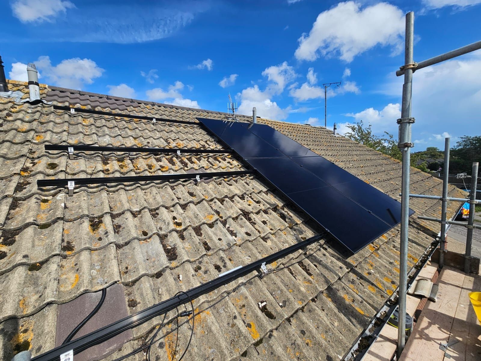 Rails fixed across a tiled roof with the first all-black panels in place